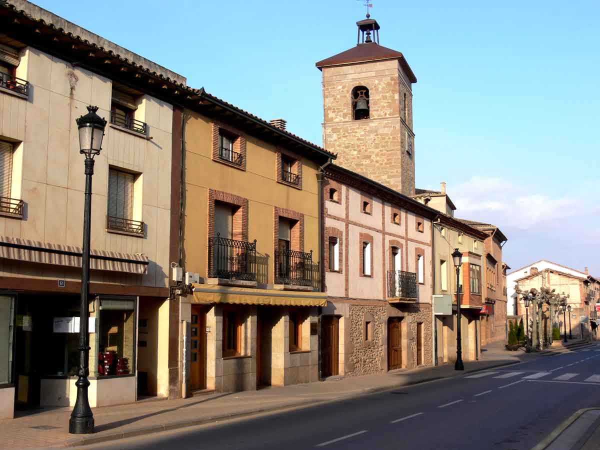 Calle del casco urbano de Badarán con viviendas tradicionales y la torre de la iglesia al fondo.