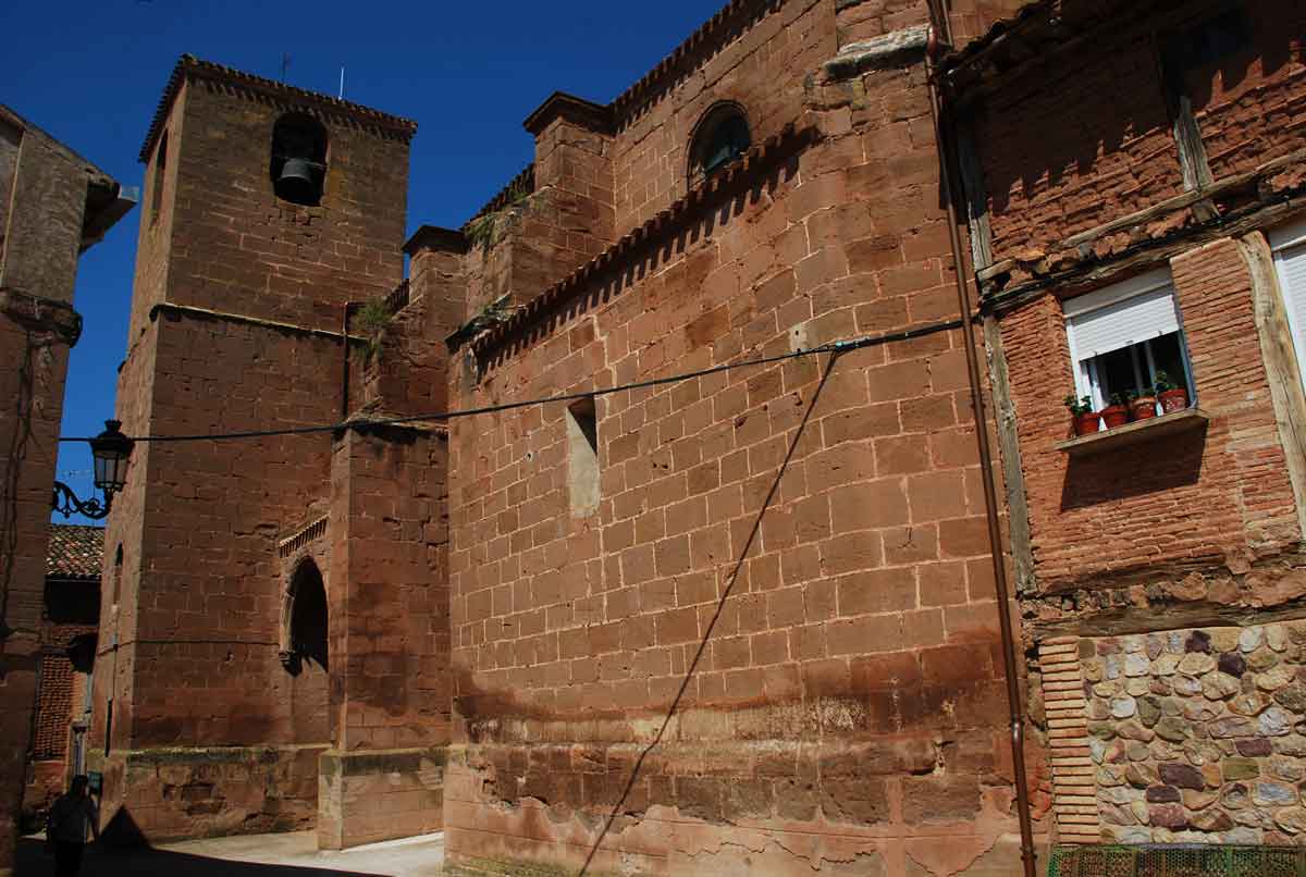 Iglesia de Nuestra Señora de la Asunción de Manjarrés junto a una vivienda tradicional del casco urbano.
