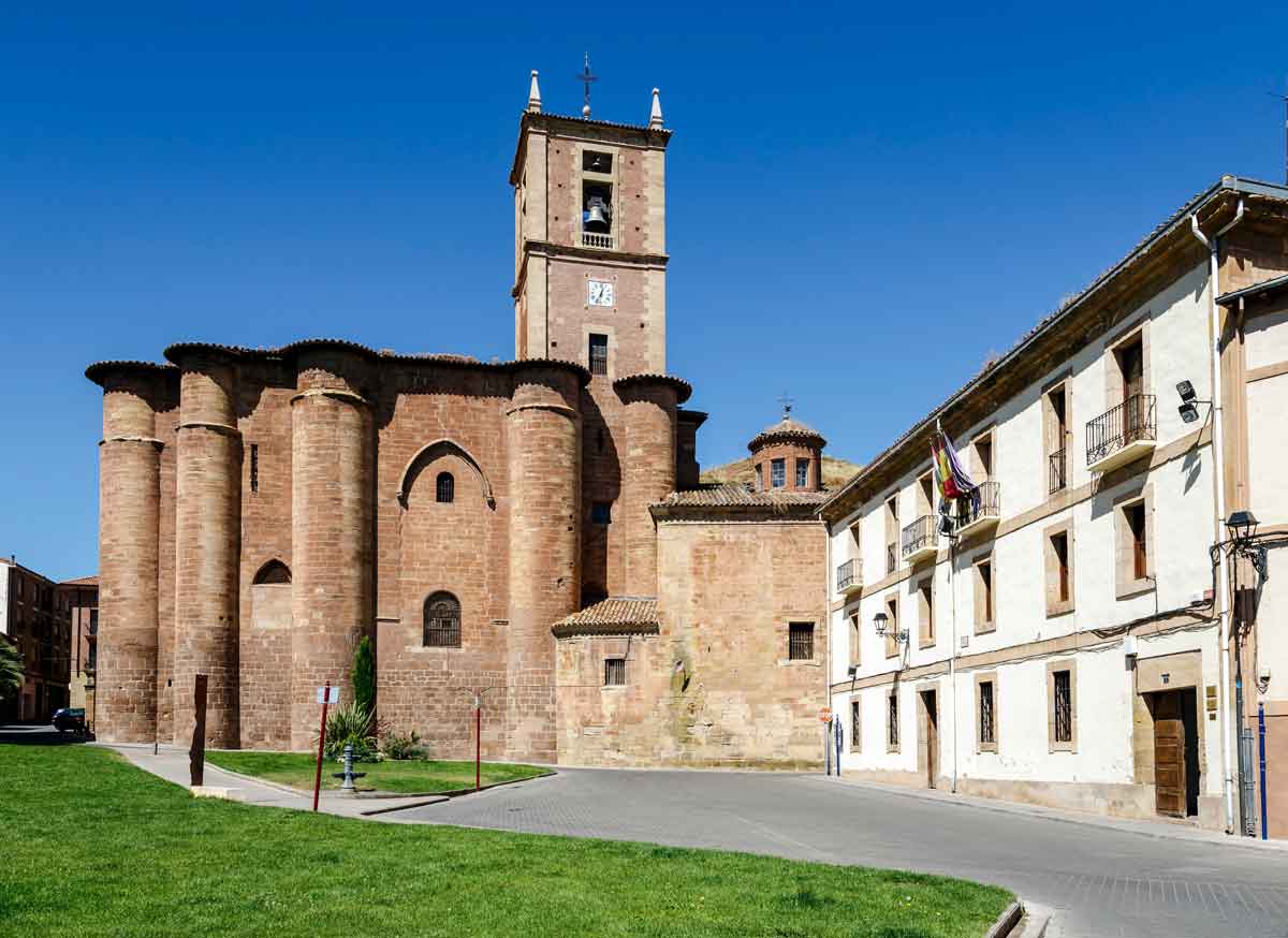 Fachada de piedra y torre del Monasterio de Santa María la Real junto al edificio del Ayuntamiento en una plaza del municipio de Nájera.