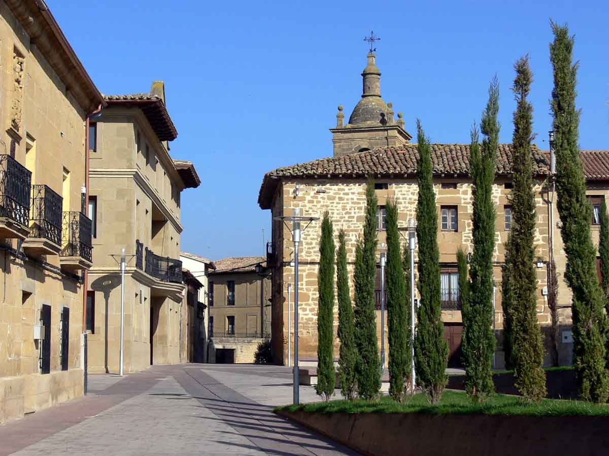 Centro urbano de Tirgo con edificios de piedra, cipreses y la torre de la iglesia al fondo
